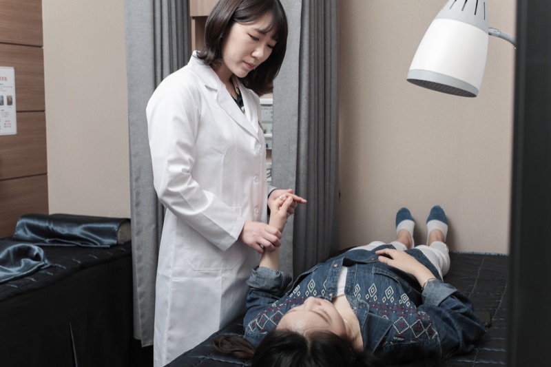리아한의원 여성 의료진이 산모의 손목 상태를 살피는 진료 장면